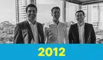 Sócios da Datatem em um escritório com vista para a cidade, com o ano 2012 destacado.